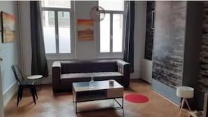 Uma sala de estar com um sofá, uma mesa de centro, uma poltrona e um tapete vermelho.