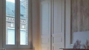 Um quarto com uma cama, janela, luminária e lareira.