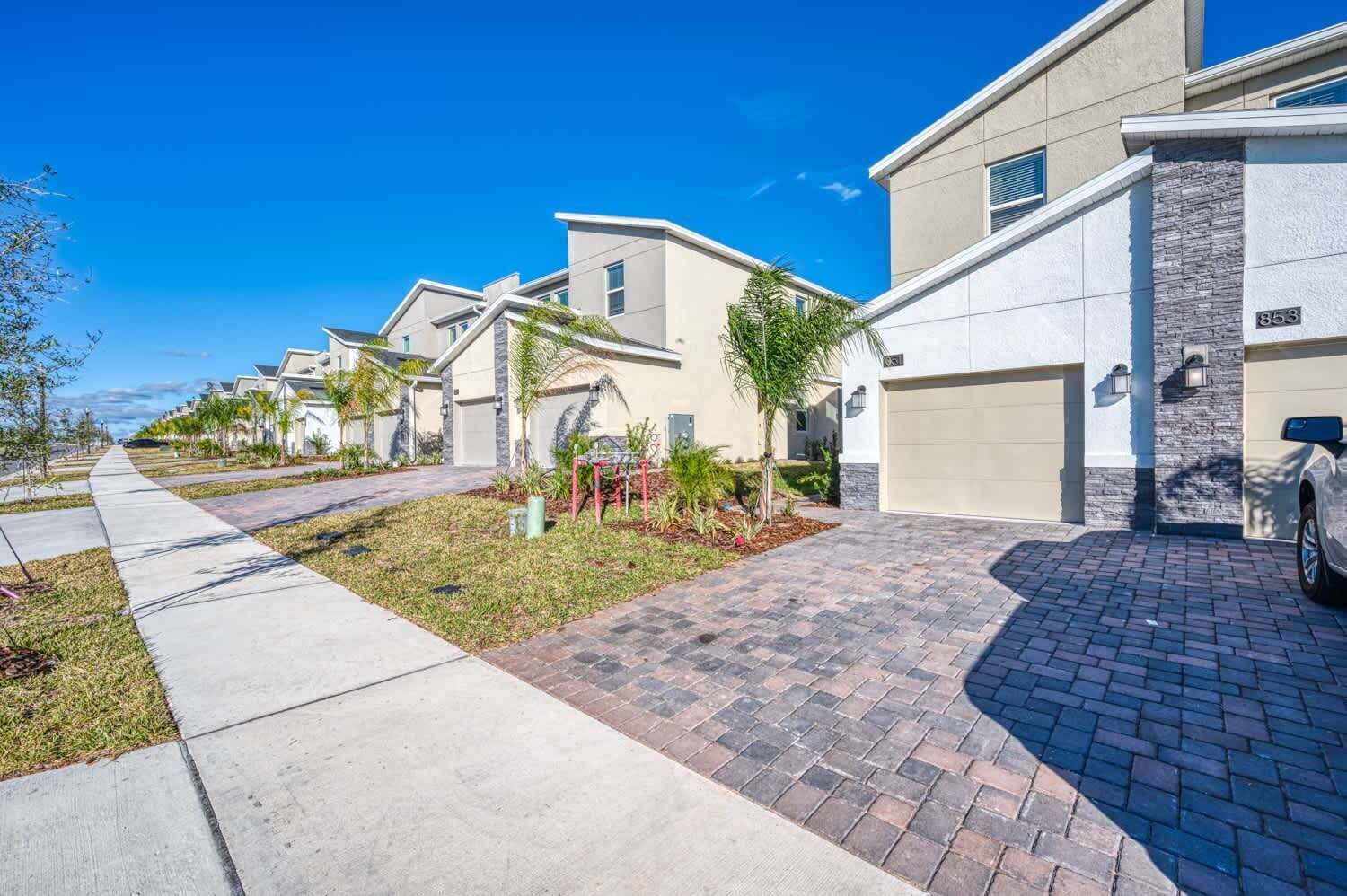 Una calle residencial con casas modernas, aceras y un camino de entrada pavimentado.