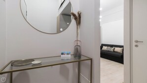 A modern bathroom with a glass vanity, a round mirror, and a vase with dried plants. - Gioberti 11 (Sesto San Giovanni)
