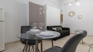 A modern living room with a glass dining table, black sofa, and a white cabinet. - Gioberti 11 (Sesto San Giovanni)