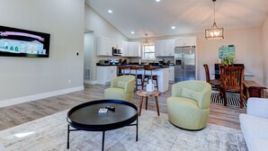 A spacious living room with a black coffee table, two green armchairs, and a dining area with wooden chairs and a table. - Cozy and Clean, Pet and Family-Friendly Gem; Minutes to Asheville (Weaverville)
