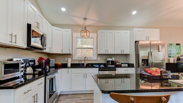 A modern kitchen with white cabinets, stainless steel appliances, a large window, and a central island. - Cozy and Clean, Pet and Family-Friendly Gem; Minutes to Asheville (Weaverville)