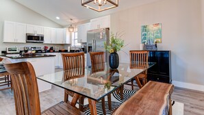 A modern kitchen with white cabinets, stainless steel appliances, and a glass dining table. - Cozy and Clean, Pet and Family-Friendly Gem; Minutes to Asheville (Weaverville)
