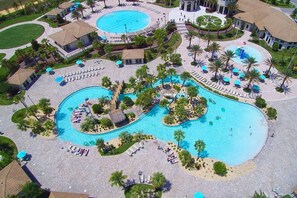 Un resort con varias piscinas, palmeras y zonas de descanso.