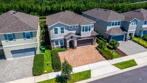 A residential area with three houses, each with a garage, a driveway, and a well-maintained lawn. - Last Minute Disney! Private Pool, Hot Tub, Game Room & Themed Bedrooms. Book Now! #31744 (Orlando)