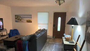 Un salon avec un canapé, un téléviseur, un tableau et une porte.