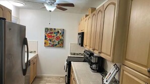 Une cuisine compacte équipée d’un réfrigérateur, d’un four à micro-ondes, d’une cuisinière et de placards.