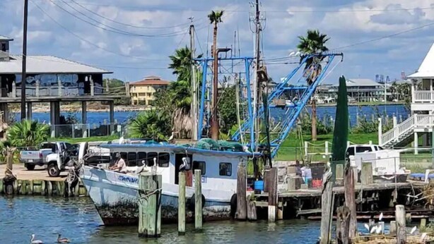 Un bateau était amarré dans une marina, avec un quai, des poteaux électriques et des immeubles d’habitation en arrière-plan.