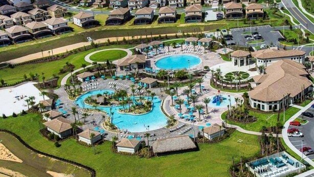 Luchtbeeld van een resort met meerdere zwembaden, een centraal waterkunstwerk en diverse resortgebouwen.
