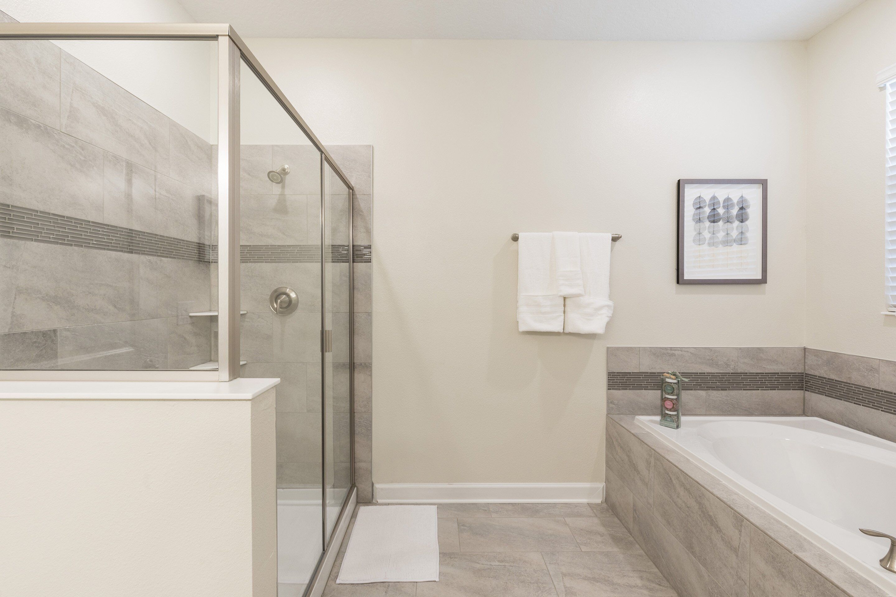 Un baño moderno con ducha acristalada, bañera y suelo de baldosas.