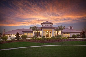 Stately Mediterranean-inspired residence with a central tower and symmetrical wings, surrounded by manicured lawns and lush greenery.