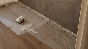 Ein Zimmer mit einem weißen Heizkörper, Holzboden und einer Wand mit Grau-Struktur.