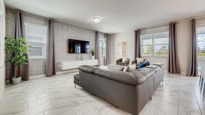 Ein modernes Wohnzimmer mit einem grauen Ecksofa, einem flachbildfernseher an der Wand und einer Topfpflanze.