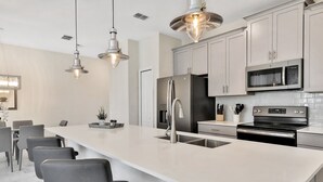 A modern kitchen with a large island, stainless steel appliances, and pendant lighting. - Last Minute Disney Getaway! Private Pool & Themed Bedrooms. Book Now! #43289 (Orlando)