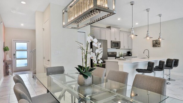 A modern kitchen with white cabinets, a central island with bar stools, and pendant lighting. - Last Minute Disney Getaway! Private Pool & Themed Bedrooms. Book Now! #43289 (Orlando)