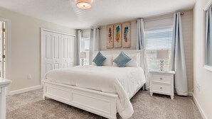 Een slaapkamer met een groot bed, een nachtkastje, een bedtafel en een plafondlamp.