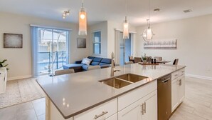 Une cuisine moderne dotée d’un îlot central, de luminaires suspendus et d’un coin repas avec une table et des chaises.