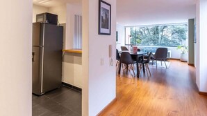 A modern kitchen with a built-in refrigerator and a dining area with a table and chairs. - w* | Homey 2BR in Cabrera (Bogotá)