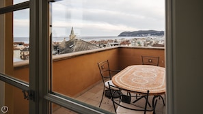 Enjoy the view of the coastal town from this balcony with a tiled table and two chairs.