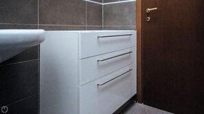 Une salle de bain avec un meuble blanc, un porte-serviettes et une porte en bois.