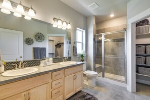 Une salle de bain avec deux lavabos, un grand miroir et une douche fermée par une paroi de verre.