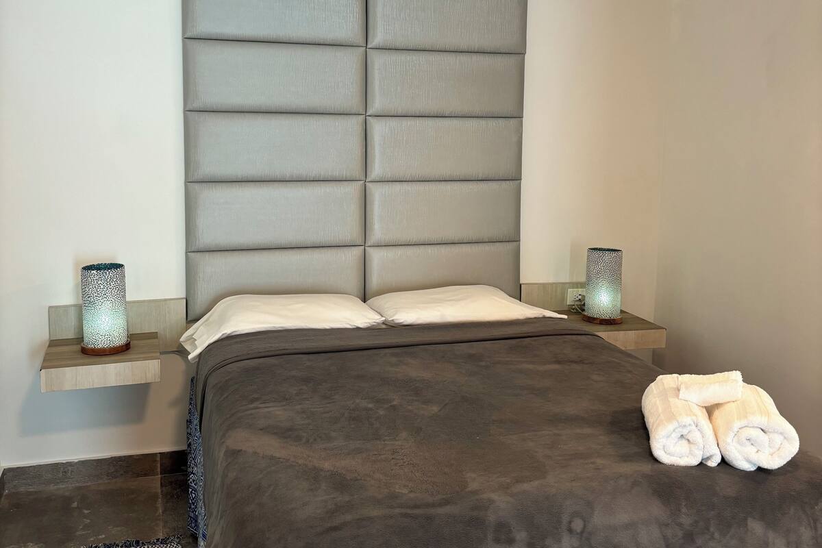 Ein modernes Schlafzimmer mit einem großen Bett, zwei Nachttischen und einem Kopfteil.