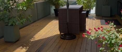 Een houten terras met plantenpotten en een tafellamp.