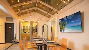 A dining area with a table set for six, a large mirror, and a painting of a beach scene. - Casa Condado Hotel & Residences (San Juan)