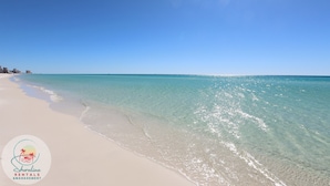 Een strand met helder turquoise water en een witte zandkust.