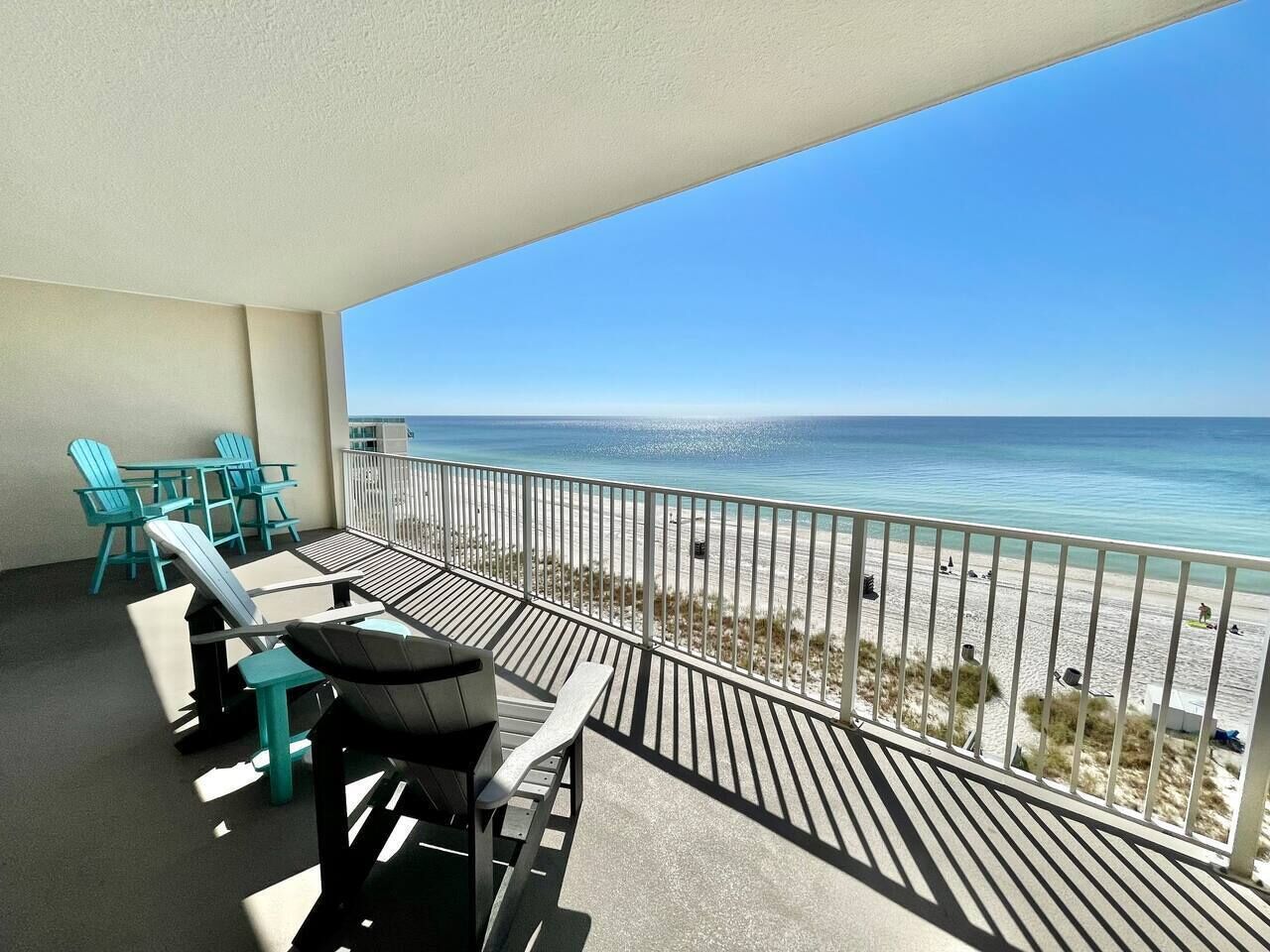 A balcony with a view of the beach, equipped with outdoor furniture and a railing.