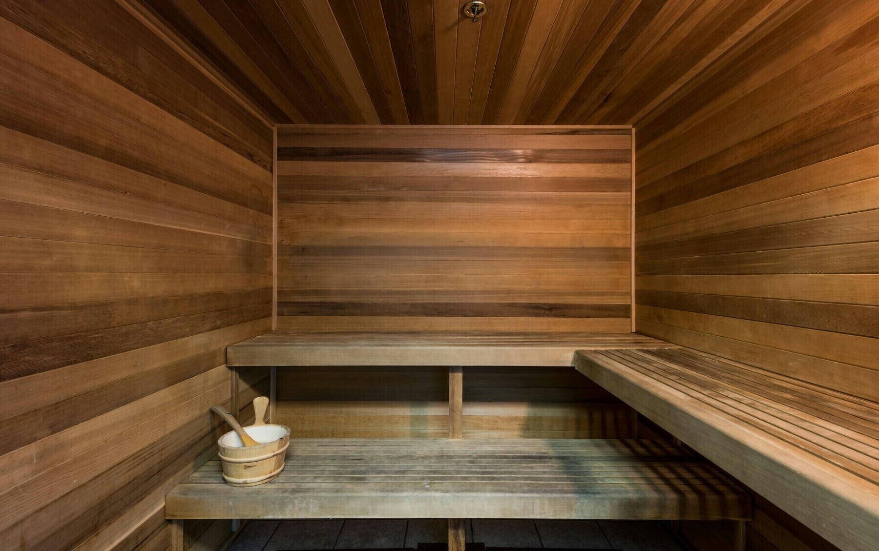 A sauna with wooden benches and a wooden bucket with a wooden spoon.