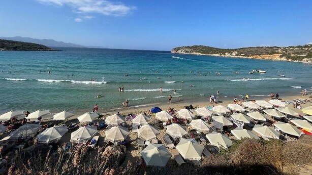 A beach with umbrellas and people.
