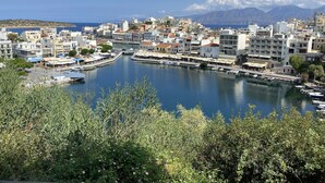 A coastal town with a marina, buildings with balconies, and a mountainous backdrop.