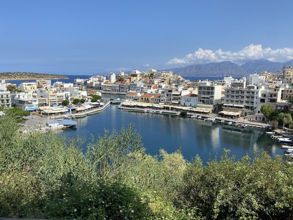 A coastal town with a marina, buildings with balconies, and a mountainous backdrop.