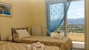 A hotel room with two beds, a view of the countryside, and a painting on the wall.