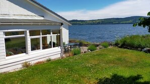Una casa blanca con un ventanal grande que da a un lago.