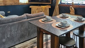 A rustic interior with a wooden ceiling, a large flat-screen TV, a sofa, and a dining table with bowls and cups. - Tawitawoo Lodge Felmoor Park (Morpeth)