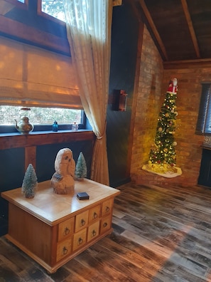 Cozy room with a rustic charm, featuring a dresser, small table, and Christmas tree.