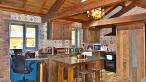 A kitchen with a wooden ceiling, tiled backsplash, and a bar area with stools. - Tawitawoo Lodge Felmoor Park (Morpeth)