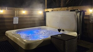A hot tub with a glass of red wine, surrounded by wooden walls and a covered area. - Tawitawoo Lodge Felmoor Park (Morpeth)