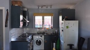 Una cucina compatta con piano cottura a gas, lavatrice e frigorifero.