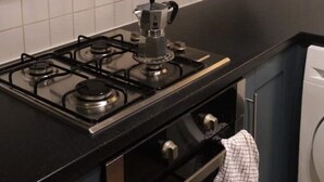 Cucina con piano cottura a gas, macchina per il caffè e lavatrice.