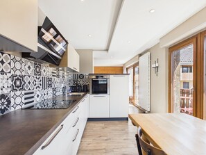 Uma cozinha moderna com painel decorativo, eletrodomésticos embutidos e uma mesa de jantar de madeira.