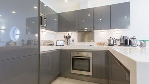 Una cocina moderna con armarios oscuros, electrodomésticos de acero inoxidable y una encimera blanca.