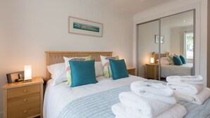 Una habitación de hotel con una cama, una mesita de noche y un espejo, además de una ventana.