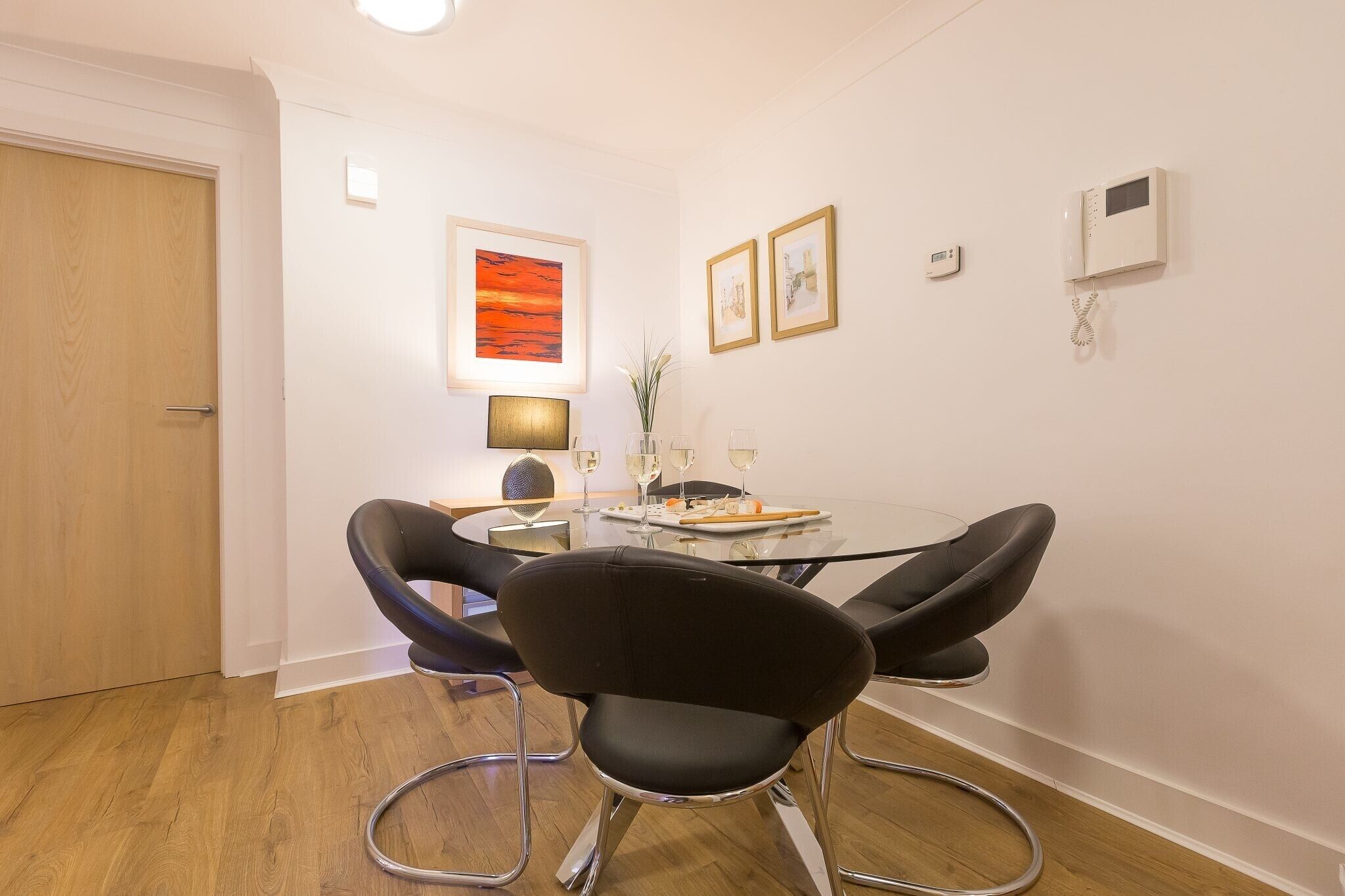 A dining area with a round table, black chairs, and a wall-mounted phone.