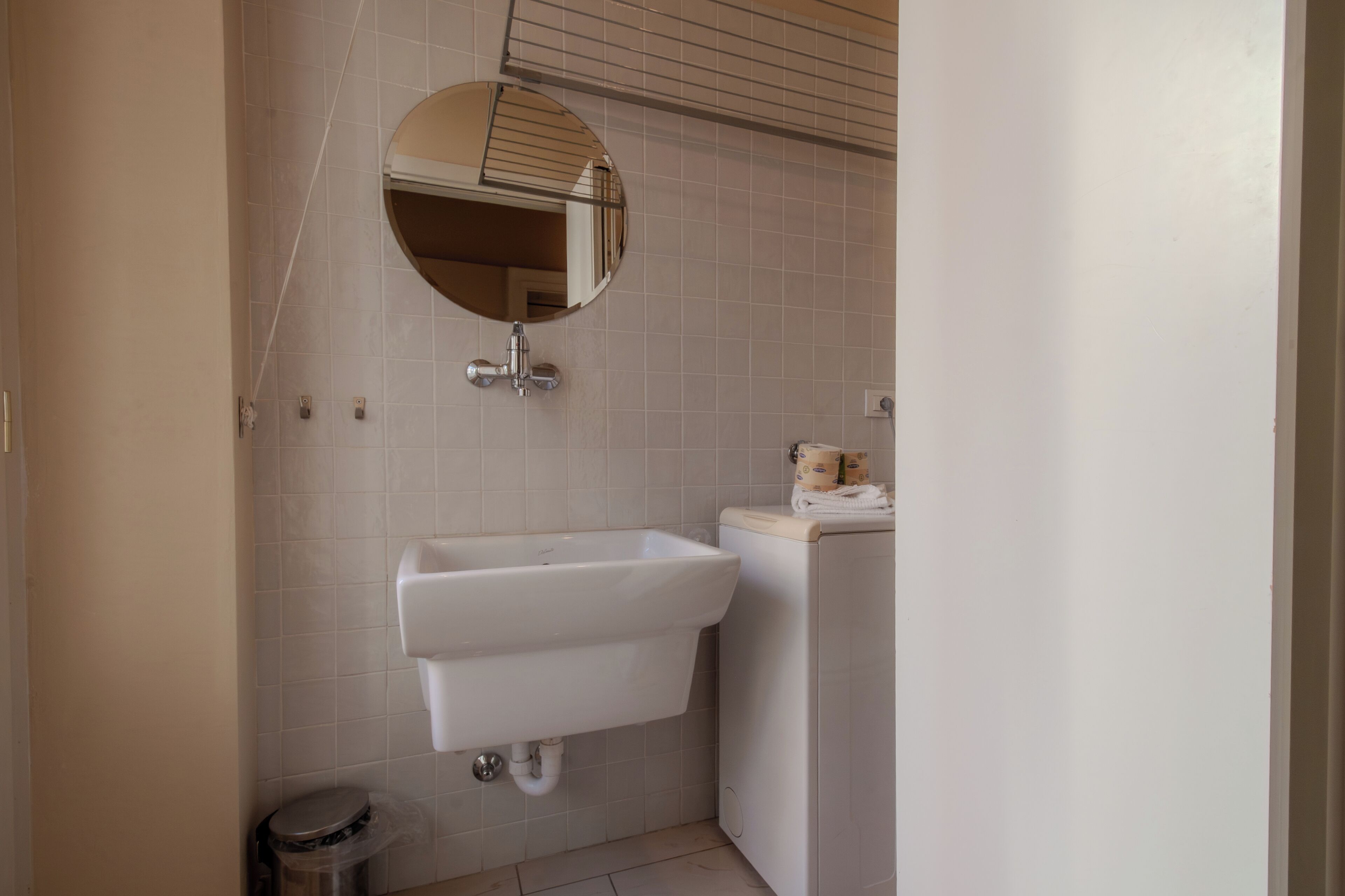 Un bagno con un lavandino bianco, uno specchio e un water.
