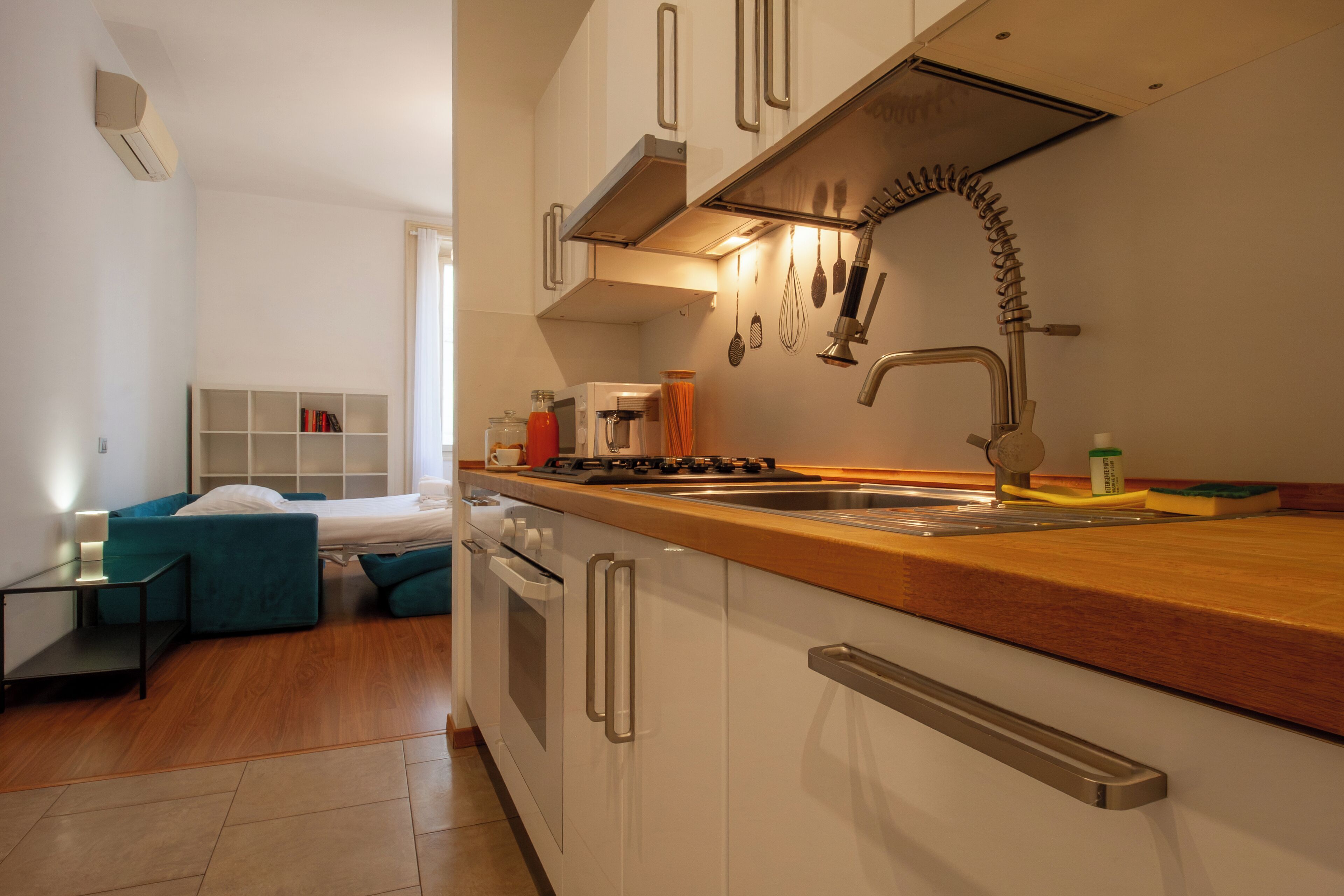Een kleine keuken met witte kastjes, een houten aanrecht en roestvrijstalen apparatuur.