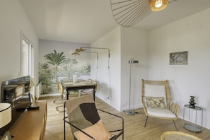 A modern living room with a dining area, a large window, and a wall mural.